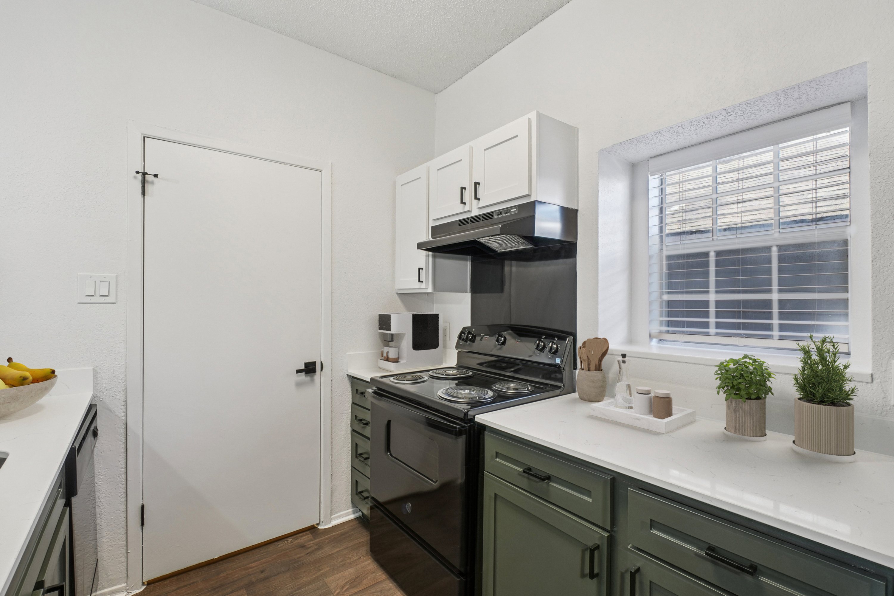 A kitchen with black appliances and white cabinets.